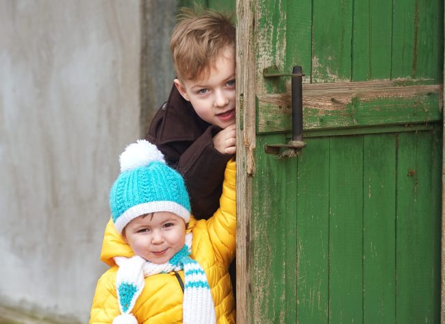 brother and sister playing with an old door